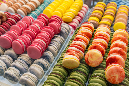 Colorful assorted macarons neatly arranged in a pastry shop display.の写真素材