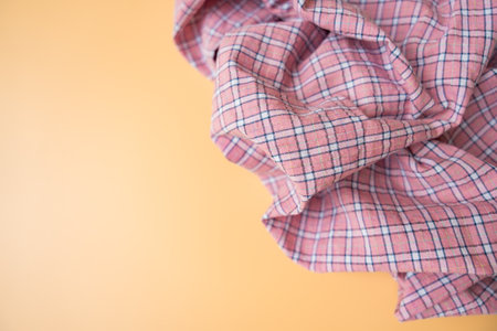 Pink plaid fabric with soft folds on beige background, textile material close-up, copy space.の写真素材