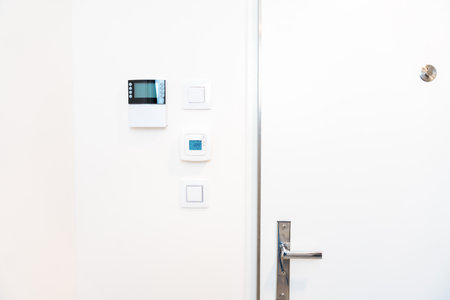 Smart home control panel and thermostat on white wall in modern interior