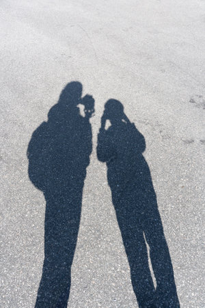 Shadow of mother and son on sunny pavement, Bergen, Norwayの写真素材