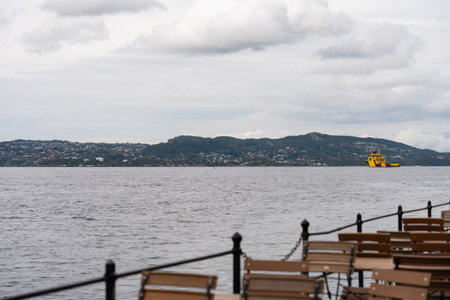 Yellow offshore vessel near Bergen coast seen from empty waterfront cafeの写真素材
