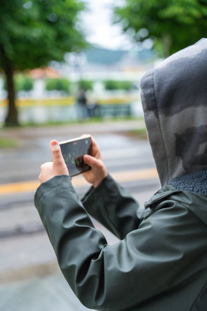 Child filming video with smartphone held horizontally in Bergen park.の写真素材
