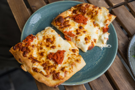 Cheesy square pizza slices on ceramic plate on wooden table in Bergen, Norwayの写真素材