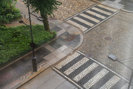 Curved cobblestone street with zebra crossings and streetlamp after rain in Bergen, Norwayの写真素材