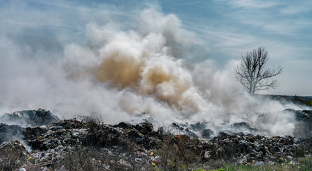 Fire at landfill with white smoke in sunny weather and clouded sky.の写真素材