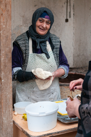 BAKU, AZERBAIJAN - FEBRUARY 2, 2019: local woman makes bread in ancient tandoor ovenのeditorial素材