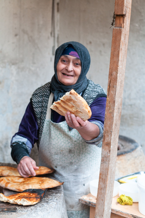 BAKU, AZERBAIJAN - FEBRUARY 2, 2019: local woman makes bread in ancient tandoor ovenのeditorial素材