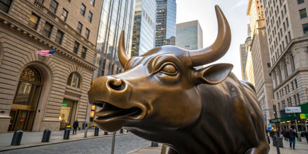 A large bronze bull statue captures attention in the Financial District, surrounded by towering skyscrapers.の写真素材
