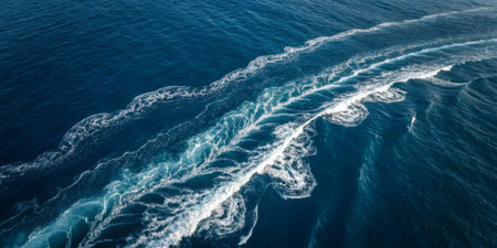 Vivid blue ocean water displays swirling white wake trails from a fast-moving boat. Bright sunlight sparkles on the surface, reflecting a tranquil and lively atmosphere.の写真素材