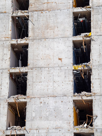 Workers maneuver around a construction site where a high-rise building is undergoing demolition.