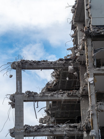 Debris and twisted metal protrude from the partially demolished high-rise building. The structure...