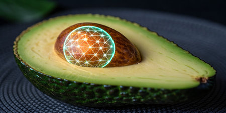 An avocado is halved, showcasing its creamy green flesh. Inside, a luminous seed features intricate...