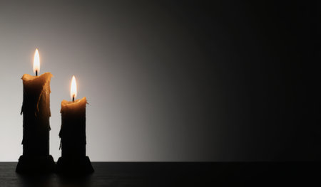 Two candles flicker gently in the darkness, their warm glow illuminating the space with a calm and peaceful ambiance. The setting creates a tranquil atmosphere perfect for relaxation.の写真素材