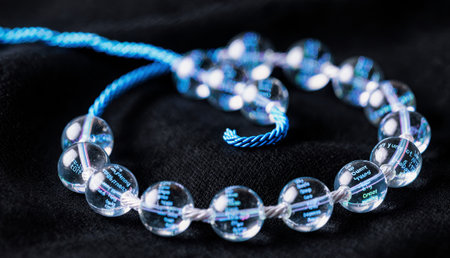 A stunning necklace features clear beads with intricate engravings, each reflecting hints of blue...