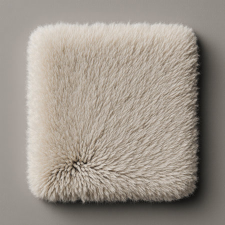 A plush cream throw pillow sits on a neutral-toned surface, inviting comfort and style. Its fluffy...