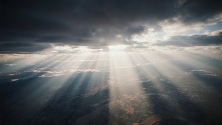 Golden rays of sunlight cascade down from the heavens, illuminating valleys and hills below. The scene captures the beauty of nature at the close of day, filled with wonder and tranquility.の写真素材