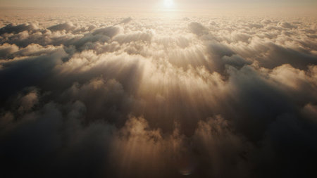 Golden rays of sunlight break through fluffy clouds, illuminating the sky in a soft glow. This breathtaking scene showcases nature's beauty during a tranquil morning above the horizon.の写真素材