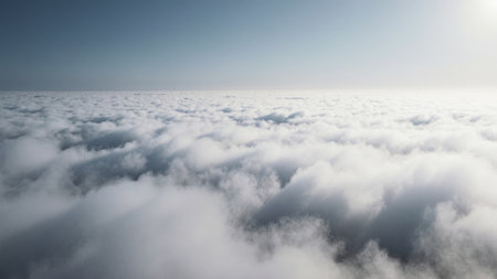 A vast blanket of soft, white clouds stretches endlessly across the horizon. The bright sun glimmers above, casting a serene light over the tranquil scene, inviting reflection.の写真素材