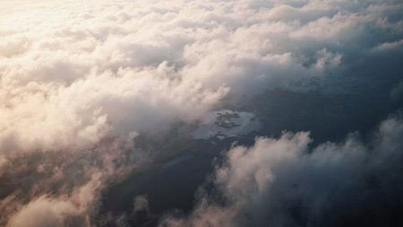 Golden sunlight filters through the fluffy clouds, illuminating the sky. This breathtaking scene captures the tranquil beauty of dawn from an aerial perspective, showcasing nature's wonders.の写真素材