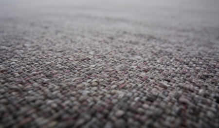 A close-up view reveals the detailed texture of a handwoven fabric. Various muted colors intertwine to form a captivating pattern, providing warmth and comfort in a cozy setting.の写真素材