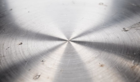 Close-up view of a polished metal surface reveals a stunning pattern of light and texture. The smooth finish highlights craftsmanship with subtle imperfections adding character.の写真素材