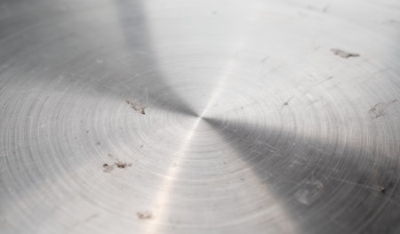 A smooth metallic surface reflects soft light, revealing swirling patterns and subtle imperfections. The interplay of light and texture creates an artistic visual display in a serene setting.の写真素材