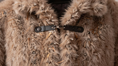 A luxurious fur coat with intricate textures and earthy tones hangs in a warm indoor space, exuding...