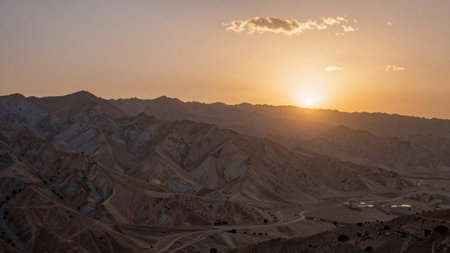 Captures a stunning sunrise over a vast, mountainous landscape, the sky is a gradient of warm...