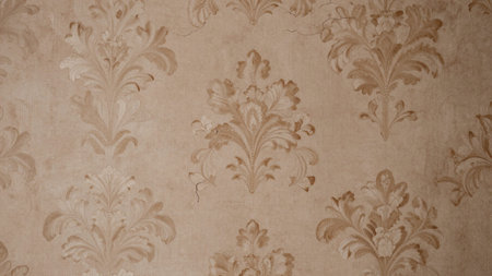Of a beige-colored, textured wallpaper with an intricate, damask pattern. The wallpaper has a...