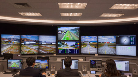 Control room with a curved ceiling and recessed lighting, the room has a dark grey wall with...