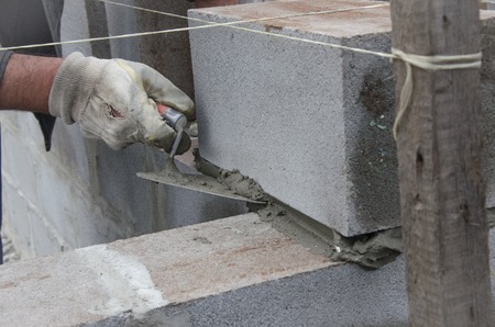 worker aligns with a spatula, lay brick cinderblocks.の写真素材