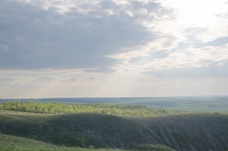 rays of the sun from behind a cloud cover the meadows and fields.