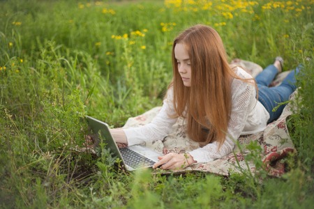 Young smiling woman with notebook in park looking at notebook computer.の写真素材