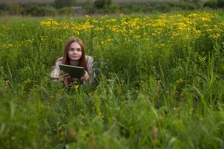 Young smiling woman with notebook in park looking at notebook computerの写真素材