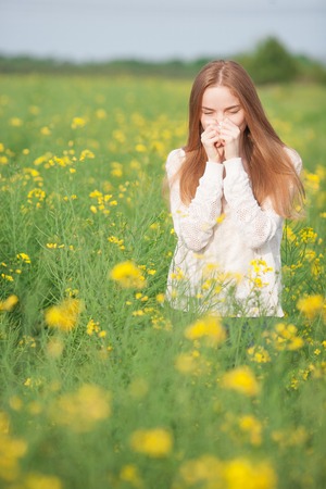 Pollen allergy, girl sneezing in a field of flowersの写真素材