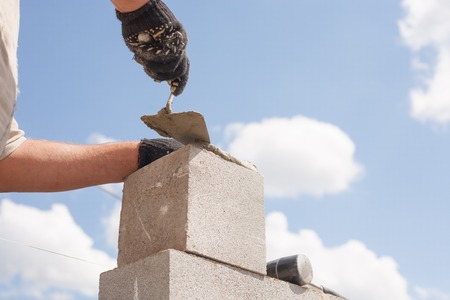 worker aligns with a spatula, lay brick cinder blocks.