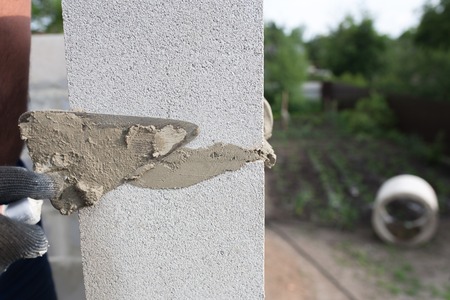 worker aligns with a spatula, lay brick cinder blocks.