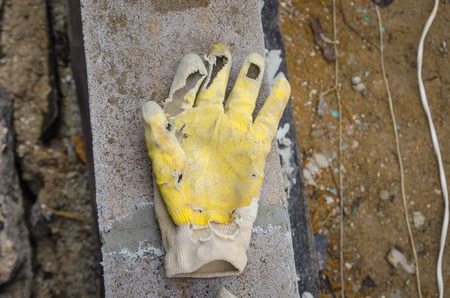 old torn dirty worker hand gloves deserted on concrete groundの写真素材