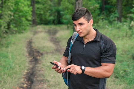 Portrait of a man traveller searching connection on the phone in the forestの写真素材
