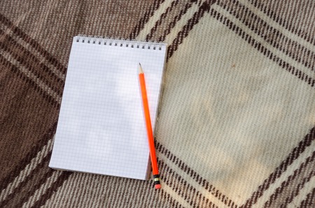 notebook with pencil and notes on coverlet in flat layの写真素材
