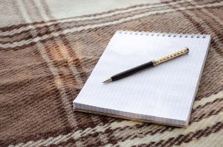 notebook with pencil and notes on coverlet in flat lay