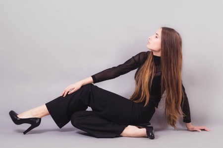 Beautiful woman in black clothes posing for the camera portrait young studio on grayの写真素材