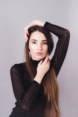 Beautiful woman in black clothes posing for the camera portrait young studio on grayの写真素材