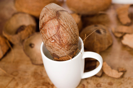 Tasty cocktail in white cup with coconut on wooden vintage table background.