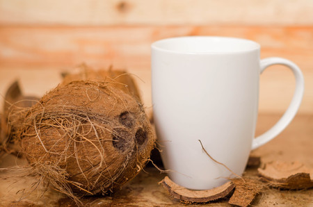 Tasty cocktail in white cup with coconut on wooden vintage table background.