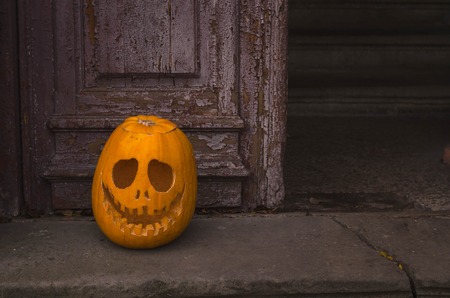 Creepy halloween scary pumpkin with a smile at the old wooden background doors.の写真素材