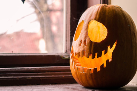 Creepy halloween scary pumpkin with a smile at the old wooden background doors.の写真素材