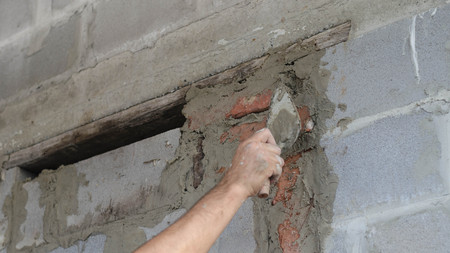 Migrant worker building cinder block wall in desert settingの写真素材
