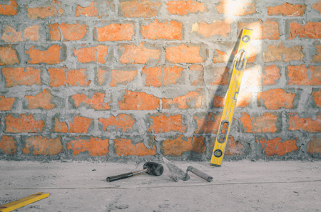 Mason bricklaying background with level, hammer and clay brick blocksの写真素材