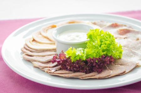 slicing meat with fresh lettuce leaves on a plate.の写真素材